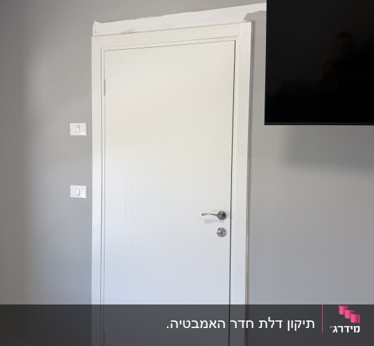 דלת פנים לבנה מעוצבת עם משקוף חדש מותקנת בקיר